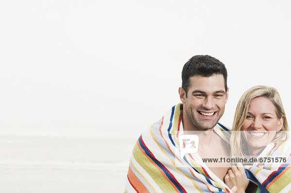 Portrait of couple wrapped in towel at beach