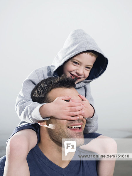 Close up of boy covering fatherÕs eyes