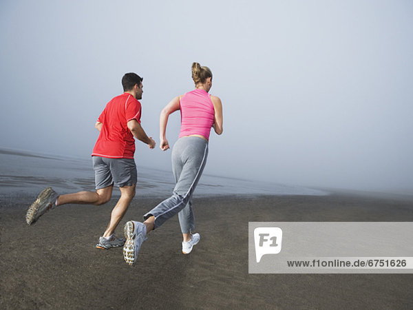 Couple jogging on foggy beach