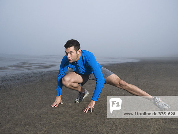 Man stretching on foggy beach