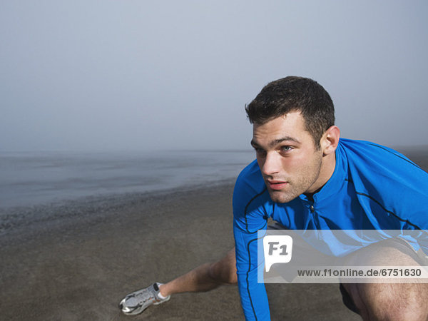 Man stretching on foggy beach