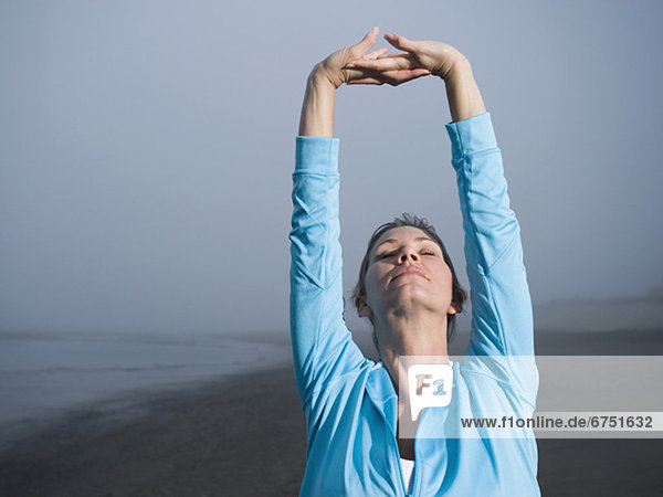 Woman stretching on foggy beach