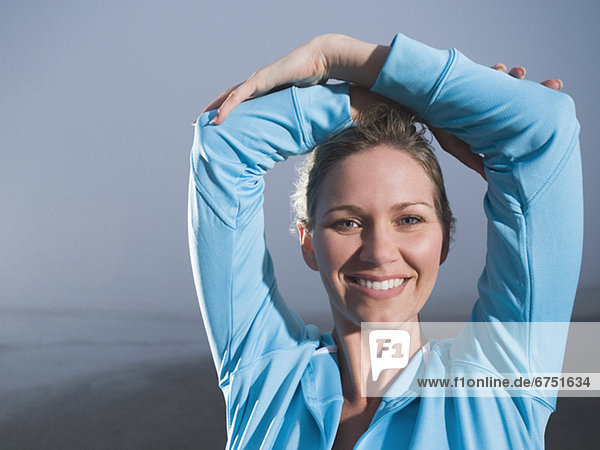 Close up of woman with hands overhead on foggy beach