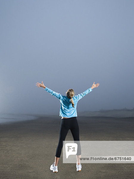 Woman with arms outstretched on foggy beach