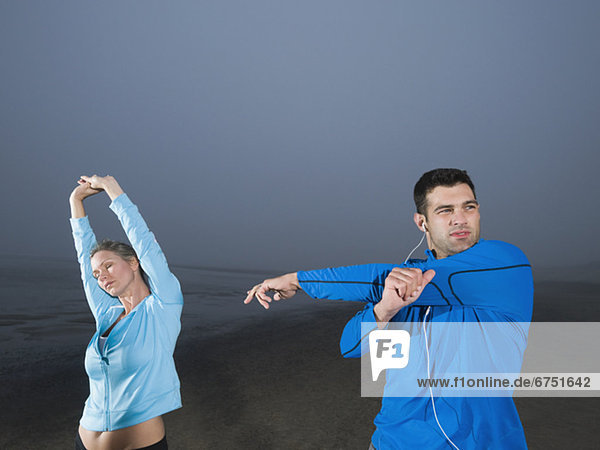 Couple stretching on beach