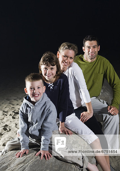 Portrait of family sitting on driftwood at beach