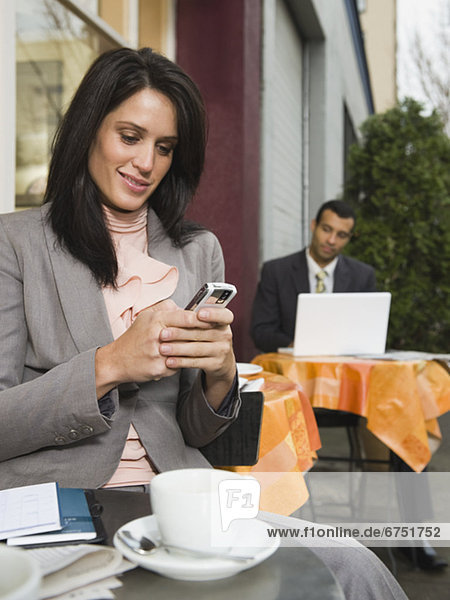 Businesswomen text messaging at outdoor cafe