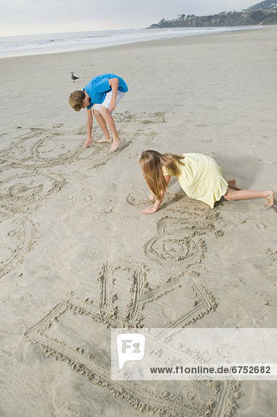 Children writing on beach