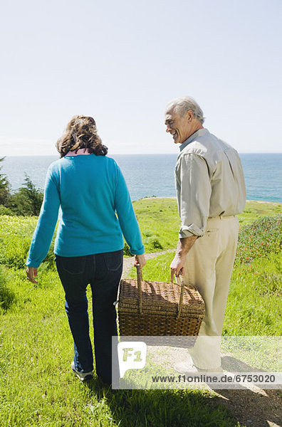Couple carrying picnic basket to the beach