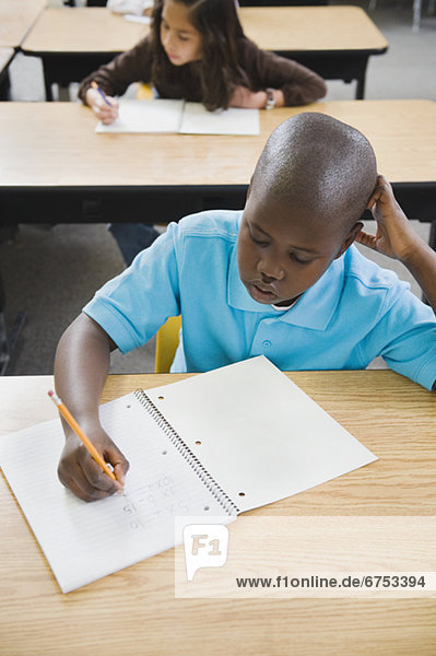 Elementary students writing in notebooks at their desks