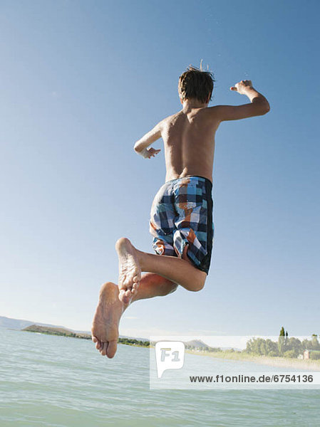 Boy (12-13) jumping into lake