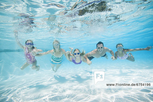 Family with three daughters (4-5 6-7 8-9) swimming underwater
