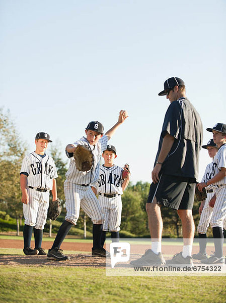 Baseball coach and boys (10-11) standing on baseball diamond