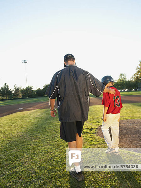 USA  California  Ladera Ranch  man and boy (10-11) walking on baseball field
