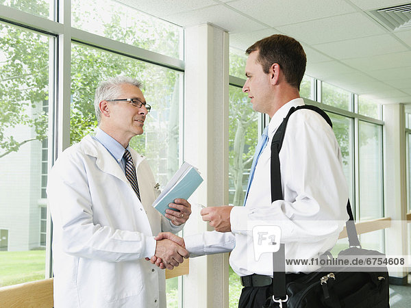 Doctor talking with pharmaceutical representative in hospital corridor