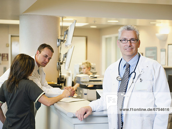 Portrait of confident doctor with two colleagues working in background