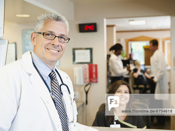 Portrait of confident doctor with female nurse in background