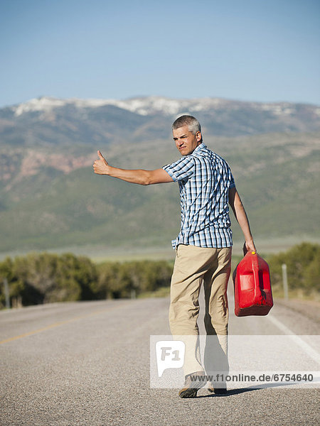 USA  Utah  Kanosh  Mid adult man carrying empty canister attempting to stop vehicles for help