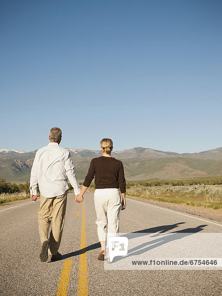Mid adult couple walking along empty road