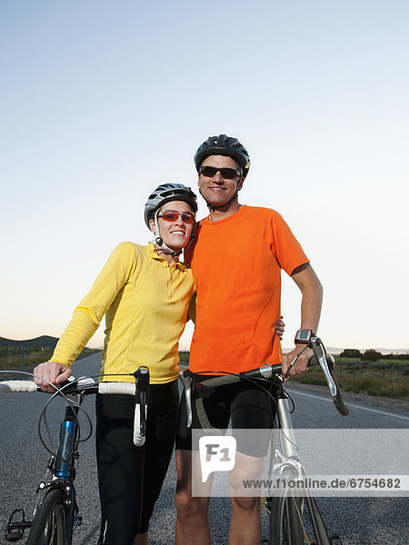 Couple of cyclists posing for portrait on empty road