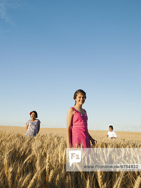 Girls (10-11  12-13) and boy (8-9) standing in wheat field