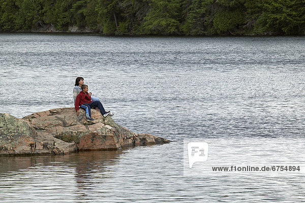 Mother and Son sitting on a Lake Rock.