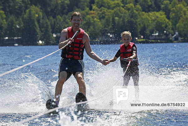 Father & Son Holding Hands while Water Skiing  Ontario
