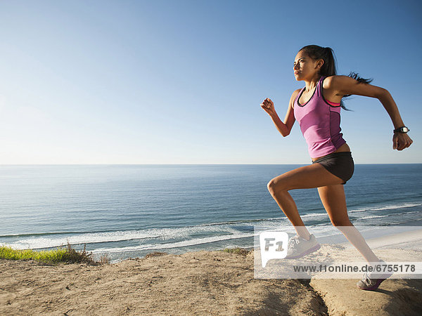 USA  California  San Diego  Woman jogging along sea coast