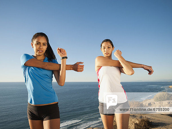 USA  California  San Diego  Two women stretching at sea coast
