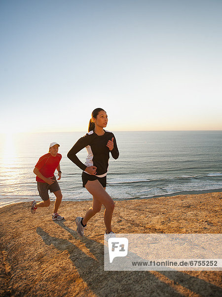 USA  California  San Diego  Man and woman jogging along sea coast