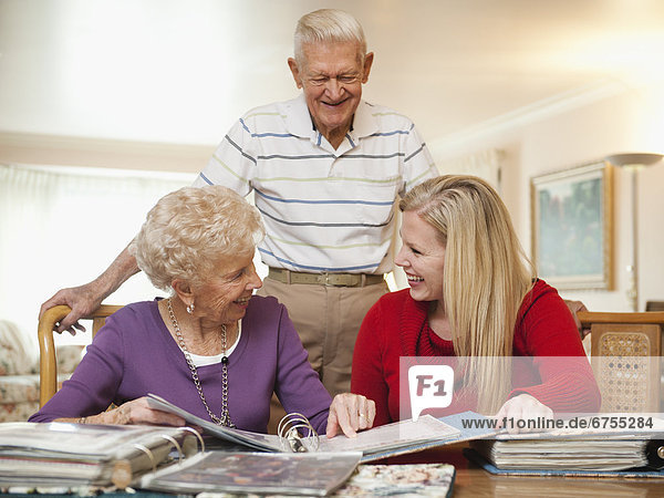 Senior couple and mid adult woman watching family scrapbooks