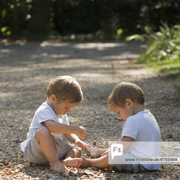 Toddler boys playing with pebbles