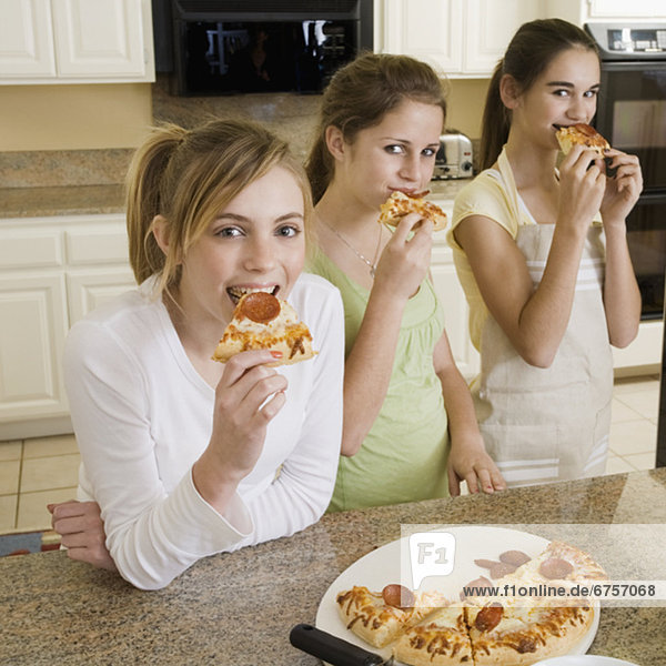 Teenaged girls eating pizza