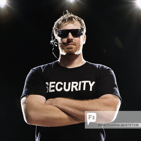 Security guard with headset posing with arms crossed