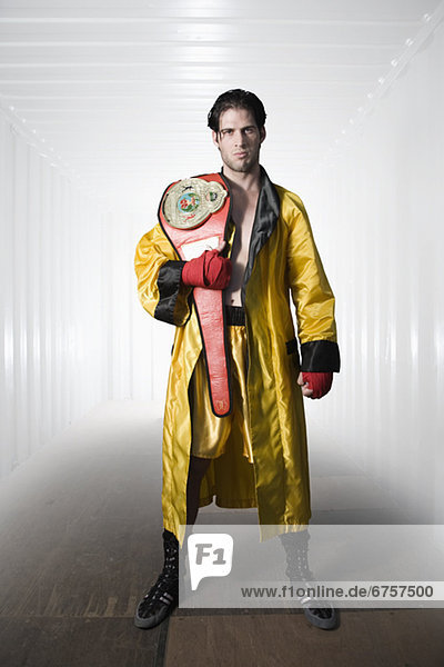 Boxer in robe posing with championship belt