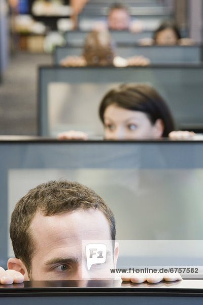 Businesspeople peeking over cubicle walls