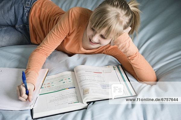 Mädchen Hausaufgaben auf dem Bett