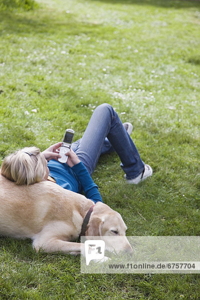 Girl leaning on dog in park