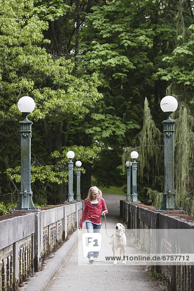 Girl walking dog across bridge