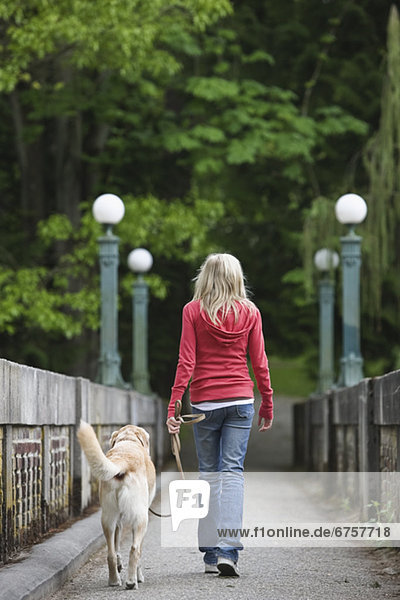 Girl walking dog across bridge