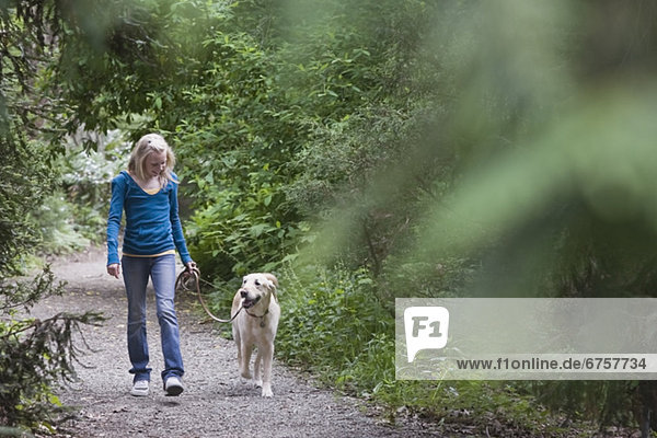 Girl walking dog on forest path