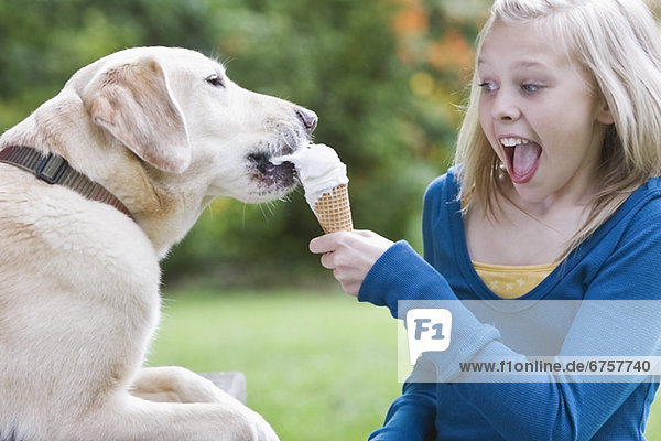 Dog eating girlÕs ice cream cone