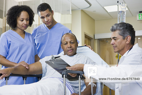 African man in hospital gurney looking at clipboard