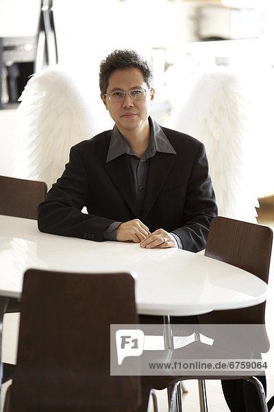 Man Wearing a Business Suit with Wings Sitting at a White Table  Montreal  Quebec