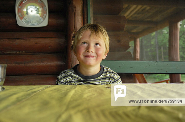 Young Boy Looking up Smiling while Sitting at a Table  Lac des Neiges  Quebec