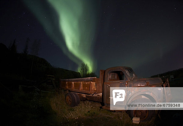 Autumn streaks of Aurora Borealis emerge from behind the rusted caracass of an old truck at the Giant Mine in Yellowknife  Northwest Territories