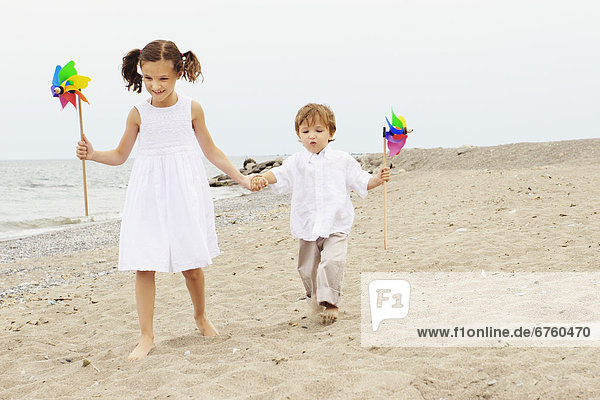 Brother and Sister walking along a Beach Holding Pinwheels  Toronto  Ontario