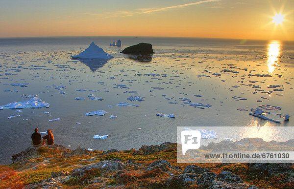 Couple looking out at an Iceberg at Sunset  Twillingate  Newfoundland