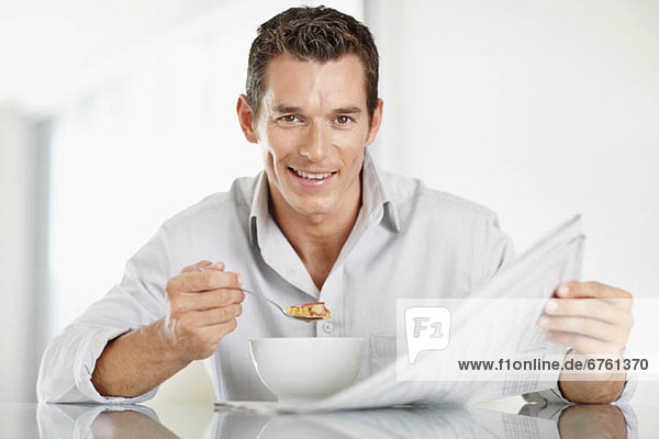 Mann  Fröhlichkeit  Mittelpunkt  essen  essend  isst  Erwachsener  Cornflakes  Zeitung  vorlesen