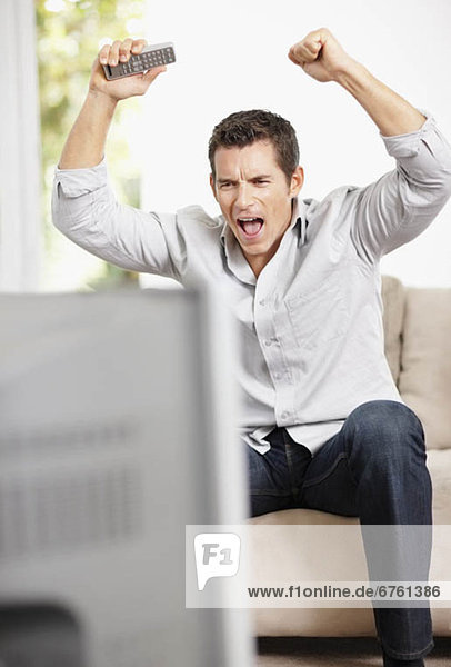 Man cheering in front of television